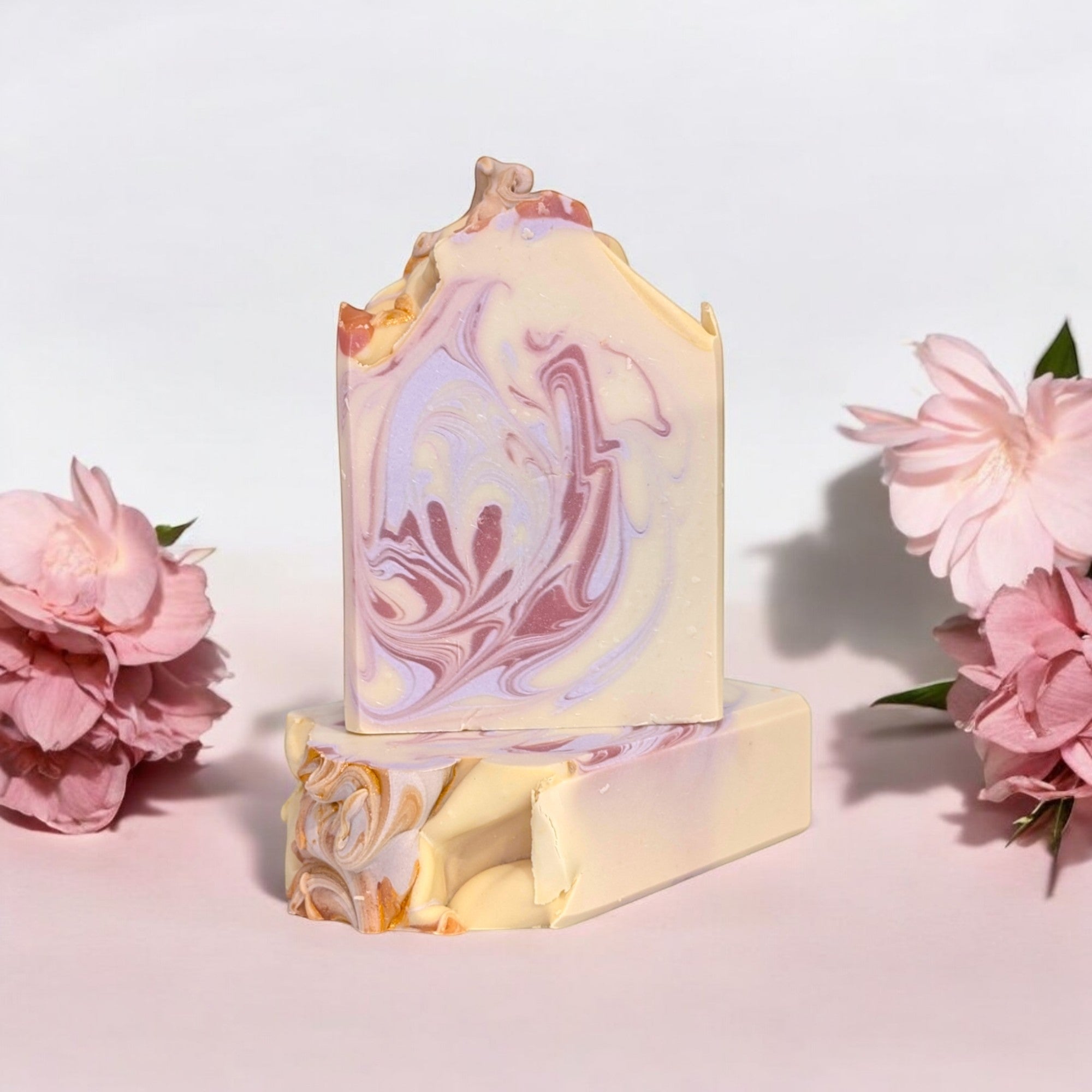 A handcrafted bar of Blossom and Bubbles soap with soft pink and white swirls, infused with notes of berries, cherry blossoms, honey, and vanilla for a romantic touch.