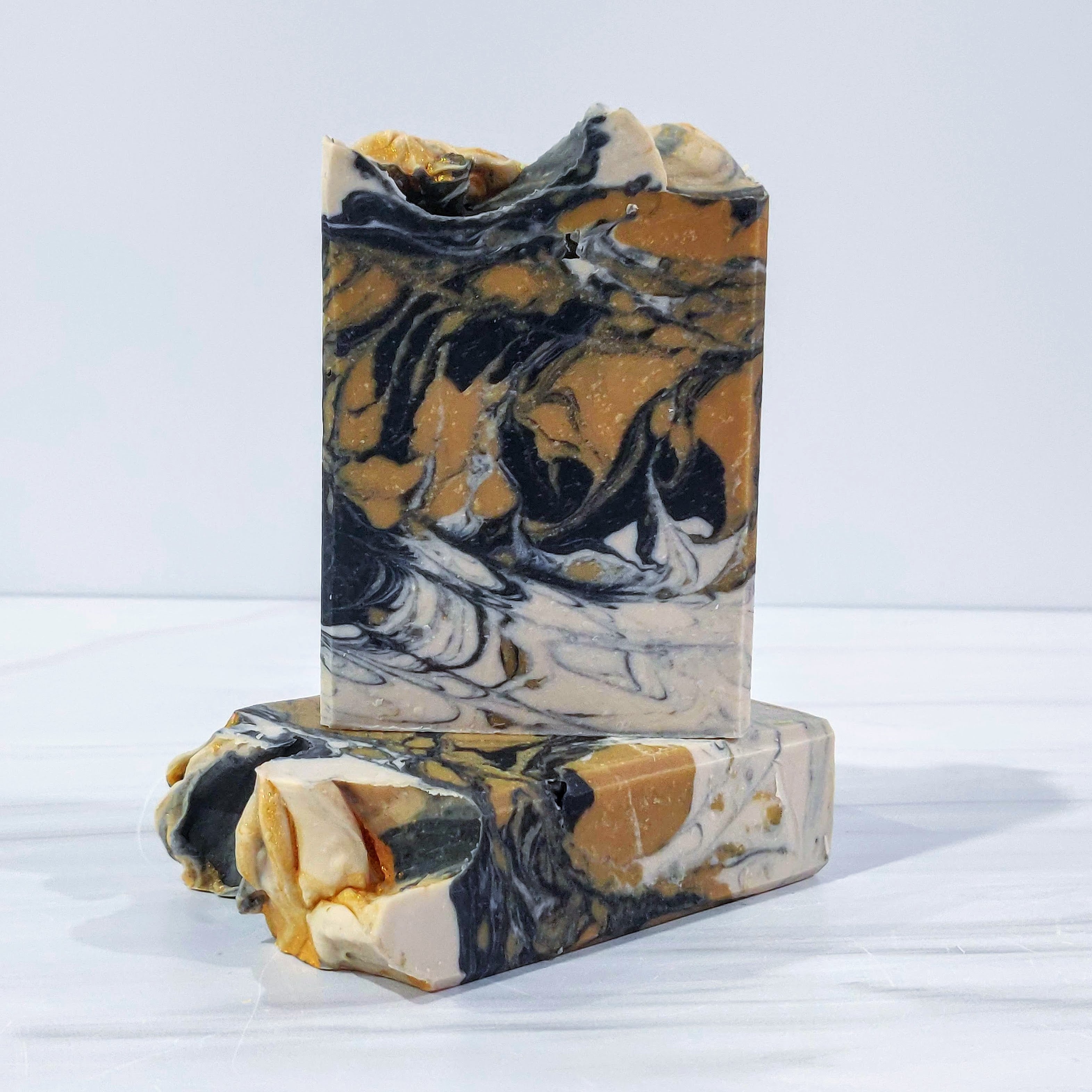 The Dapper Heart artisan soap, featuring bold swirls of black, gold, and cream, infused with an alluring blend of warm amber, rich oud, smoky vetiver, and a hint of citrus. Handcrafted for a luxurious and sophisticated cleansing experience, perfect for those who appreciate refined grooming and deep, masculine scents.